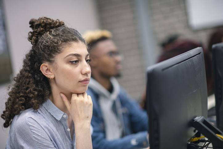 A multi-ethnic group of students are working on a university assignment. They are researching potentials for their thesis.  They are wearing casual clothes. The room is located on the university campus.